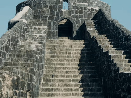 A stone fort structure with stairs leading up to an arched entrance.