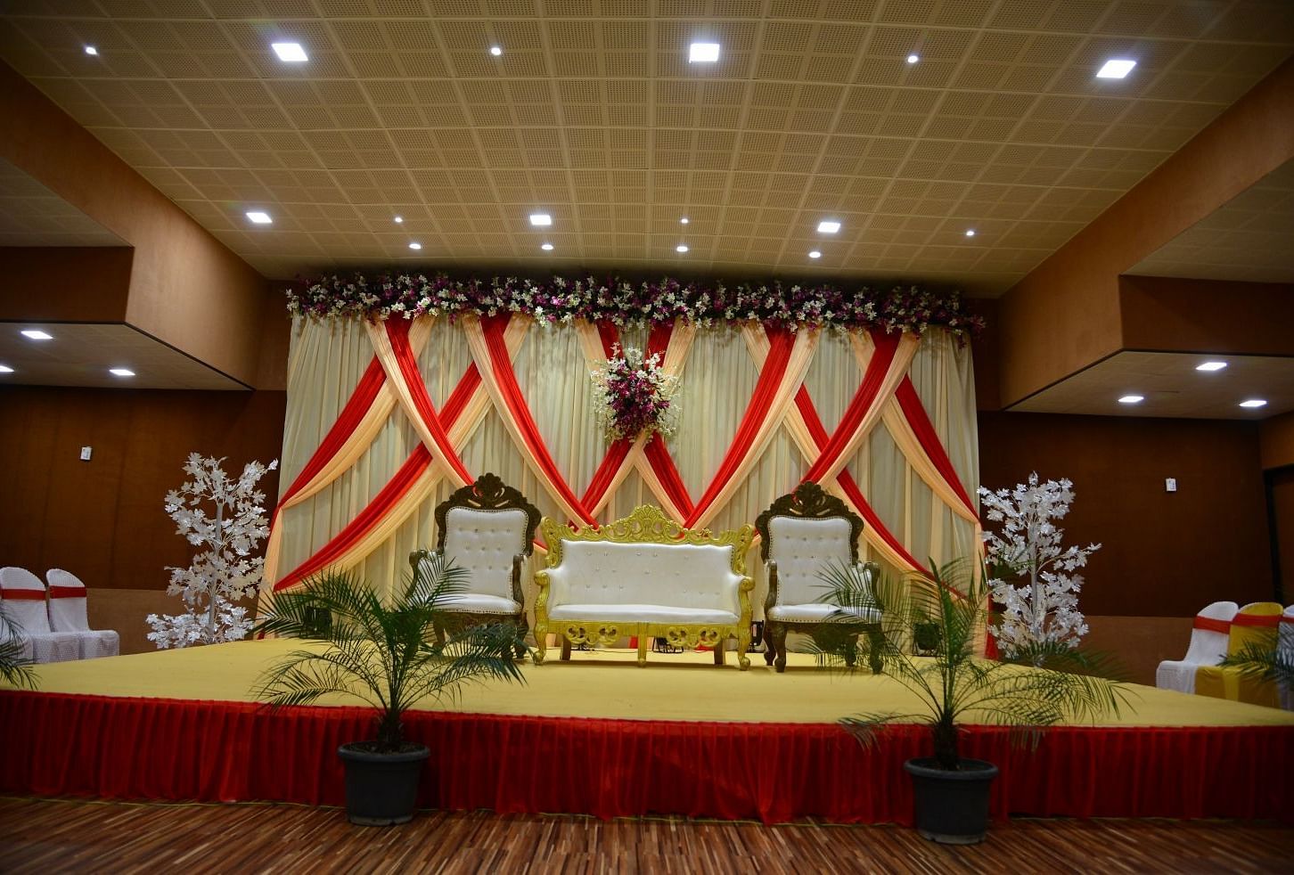 The stage of the wedding area decorated with fancy furniture, curtains, and flowers.