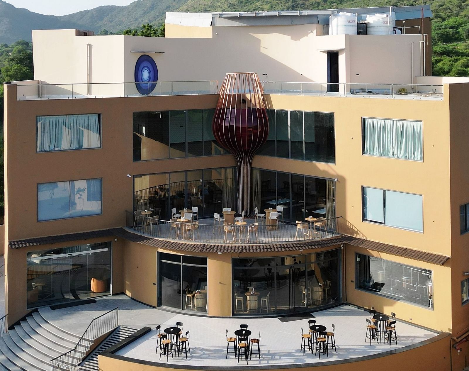 The Qualia Resort Club & Brewery, Udaipur with a terrace and outdoor seating is shown in daylight.