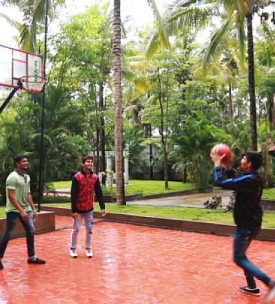Image of three people playing basketball with trees in the background.
