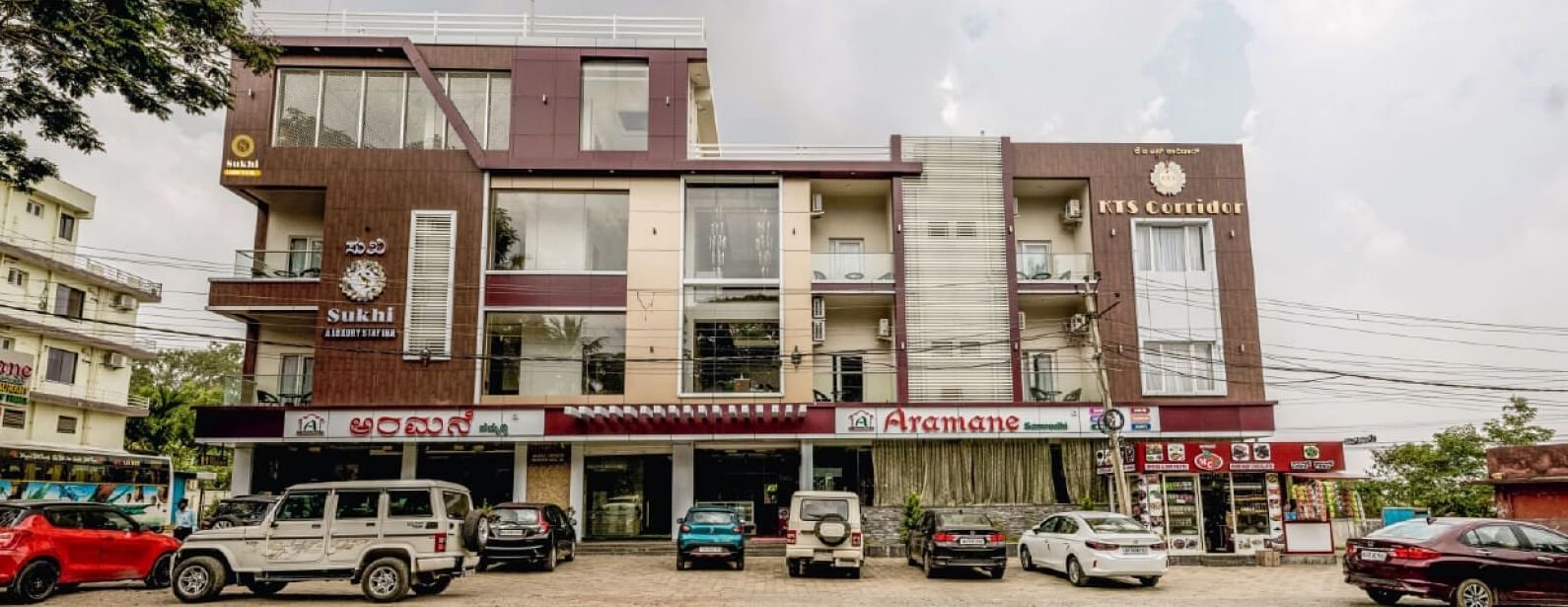 Facade image of Sukhi - A Luxury Stay Inn, Chikkamagaluru with several vehicles parked in the front.