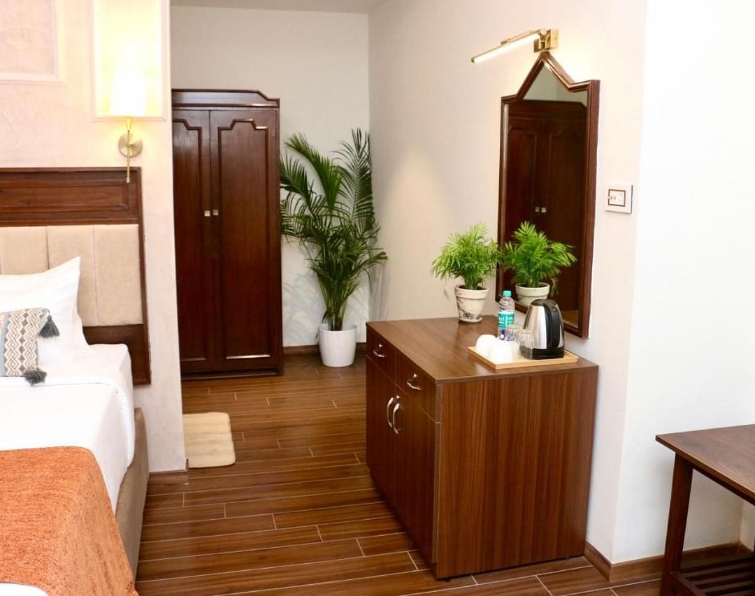 A corner of Luxury Twin Room in Nalapad's Hotel Bangalore International, featuring wooden furniture and plants.