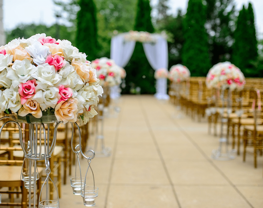 Elegant outdoor wedding ceremony setup with floral arrangements and an aisle.
