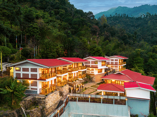 Voyage Songfum Retreat, a hilltop resort with red-roof cottages and balcony rooms, surrounded by lush green mountains and scenic valley views.