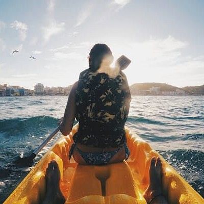 A shot taken from a kayak showing a person kayaking in rough waters, on a sunny day.