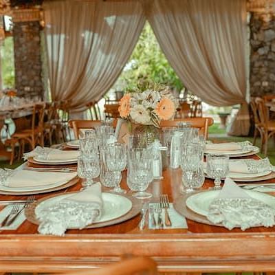 Banquet hall with wooden dining table filled with cutlery and plates and glasses.
