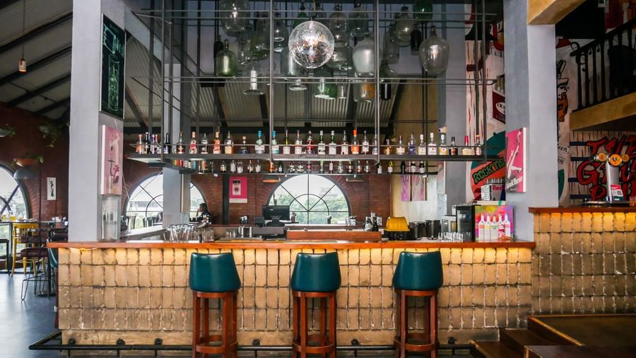 A vibrant hotel bar with stylish high chairs and a well stocked counter, ready for drinks at Shilton Dee Cee.