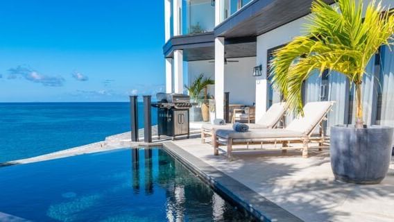 A private villa boasts an inviting infinity pool seamlessly blending with the ocean horizon.
