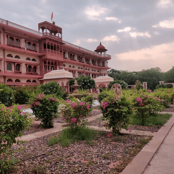 The grand facade of the Umaid Palace resort stands elegantly behind a beautifully manicured heritage garden.