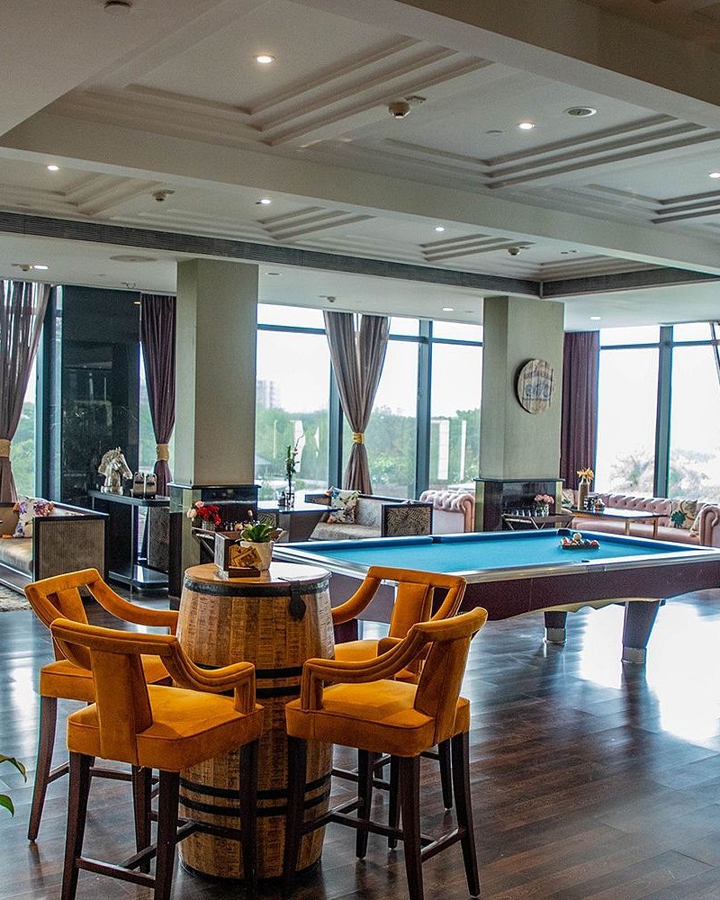 Indoor lounge area at Karma Chalets featuring a pool table, bar stools, and large windows with natural light.