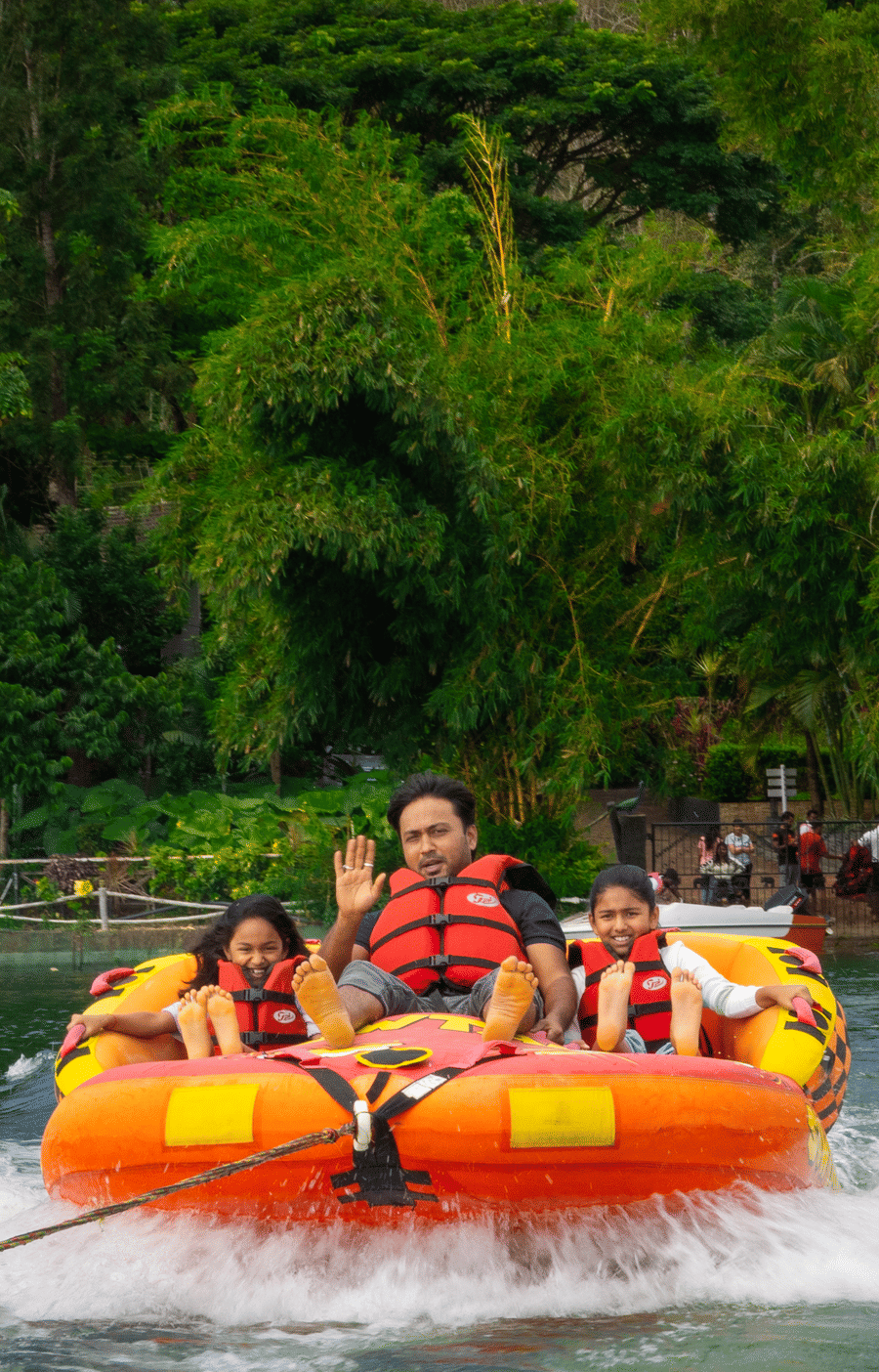 Image of a man and two girls on a boat with trees in the background.