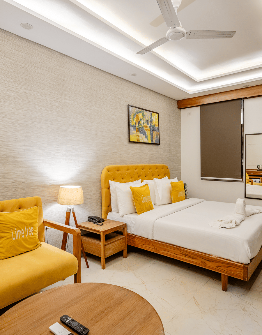 Cozy hotel room setup with a yellow sofa chair, white bedding, and ambient lighting.