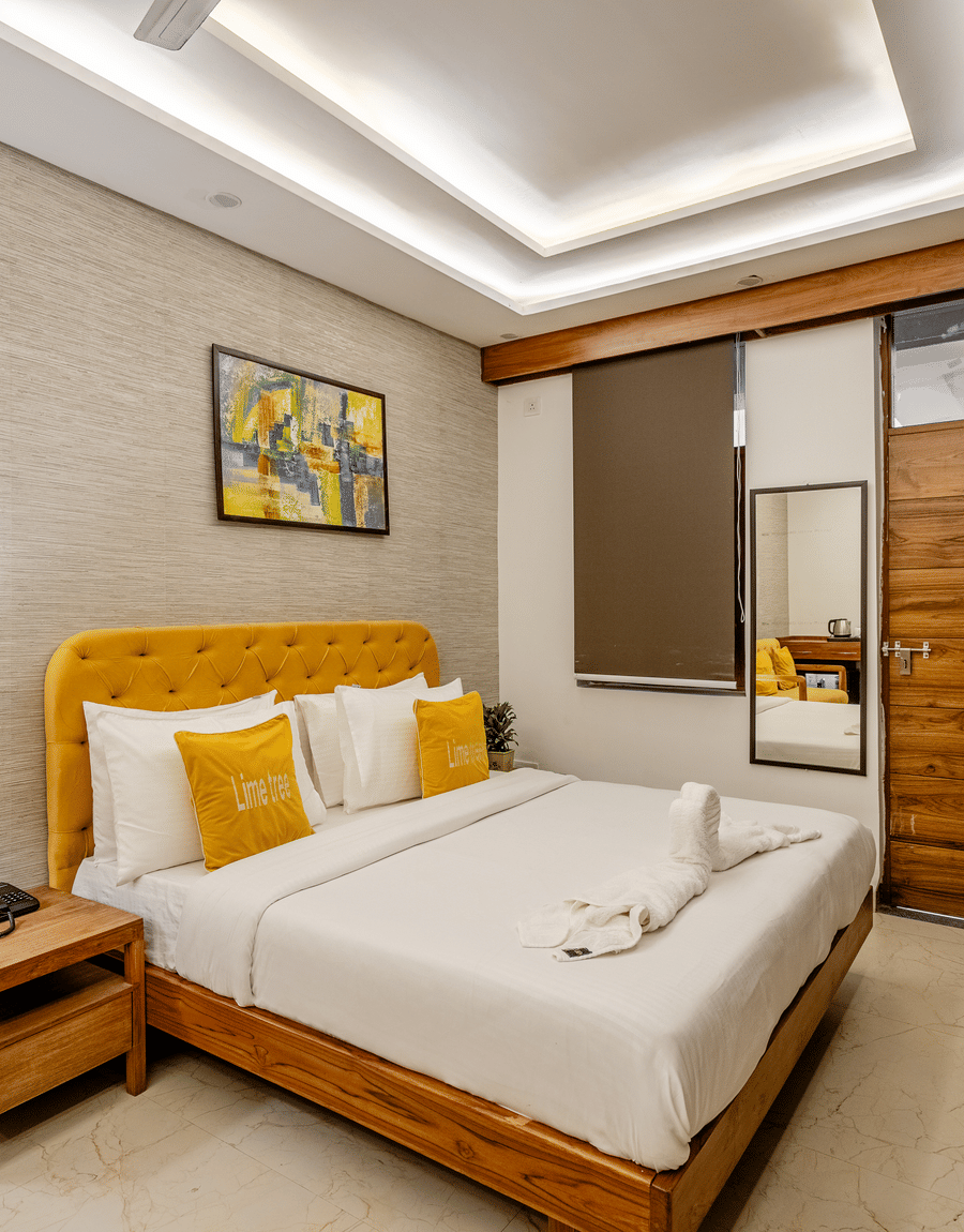 Stylish hotel room interior showing a double bed, wooden furniture, and elegant wall decorations.
