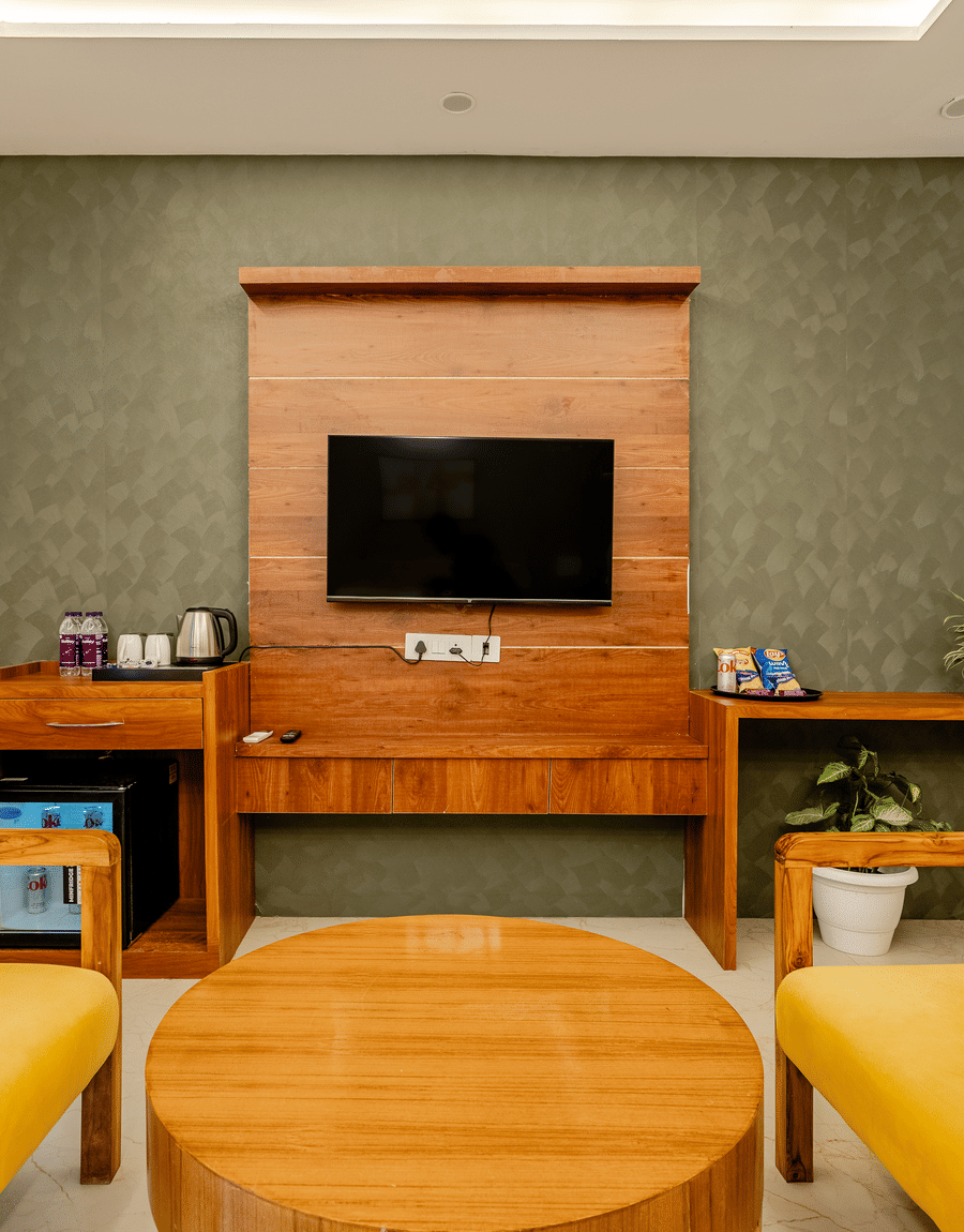 Comfortable in-room lounge area featuring yellow armchairs, a circular coffee table, and a wooden media console.