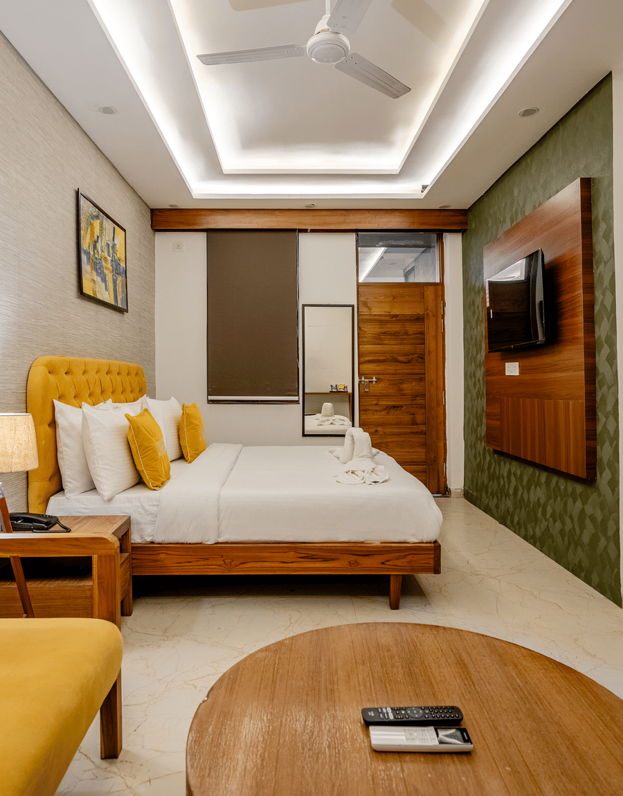 Modern hotel bedroom interior featuring a plush bed, yellow accents, and a wooden table.