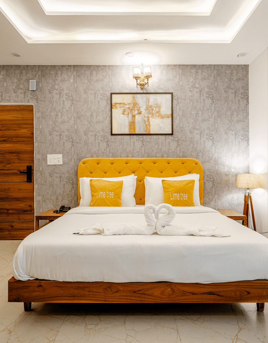 Double bed with a bright yellow headboard, white linens, and elegant grey wallpaper backdrop.