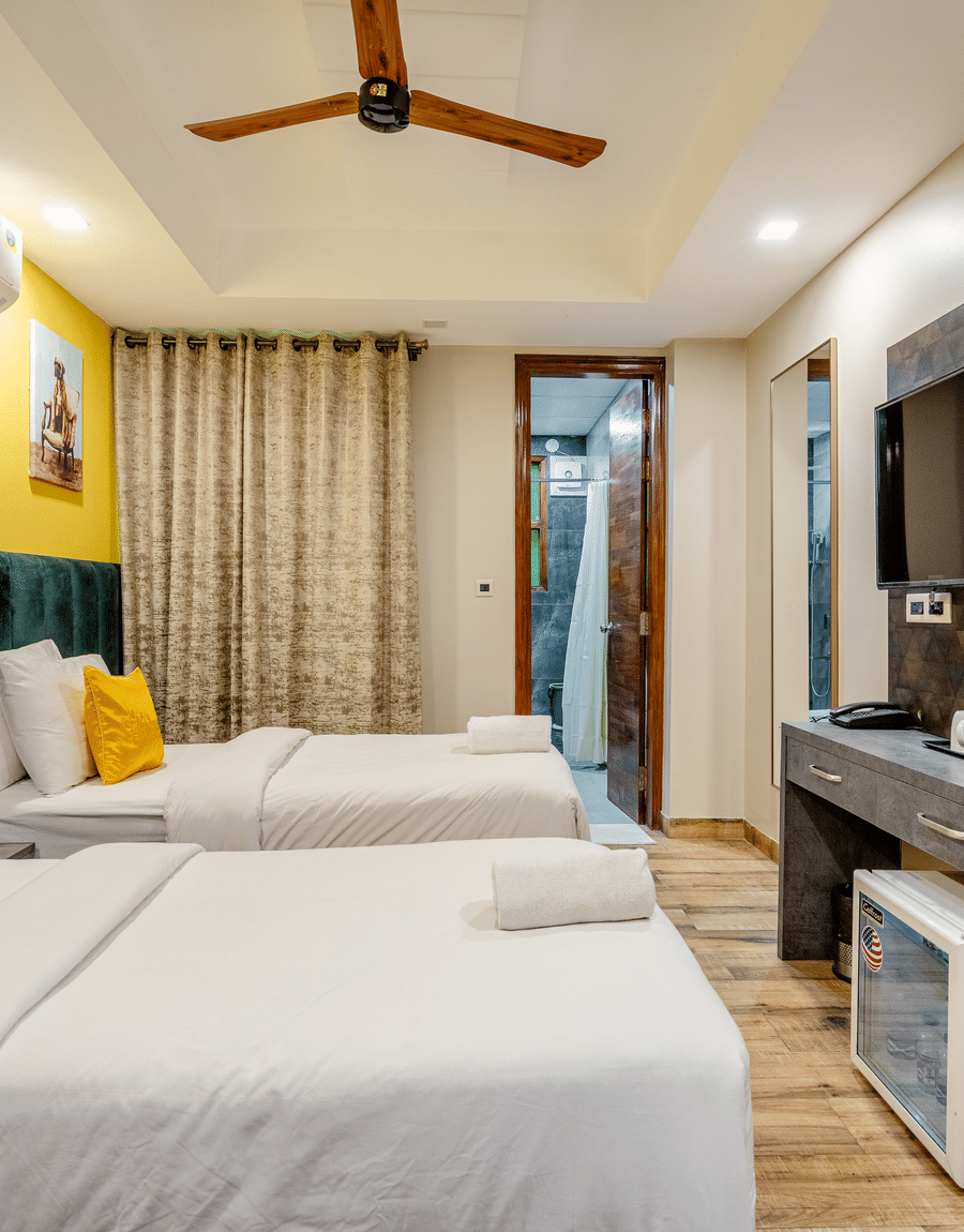 Deluxe Twin Room with twin beds, a green headboard and a wall-mounted TV at Lime Tree Hotel Near Medanta, Gurgaon