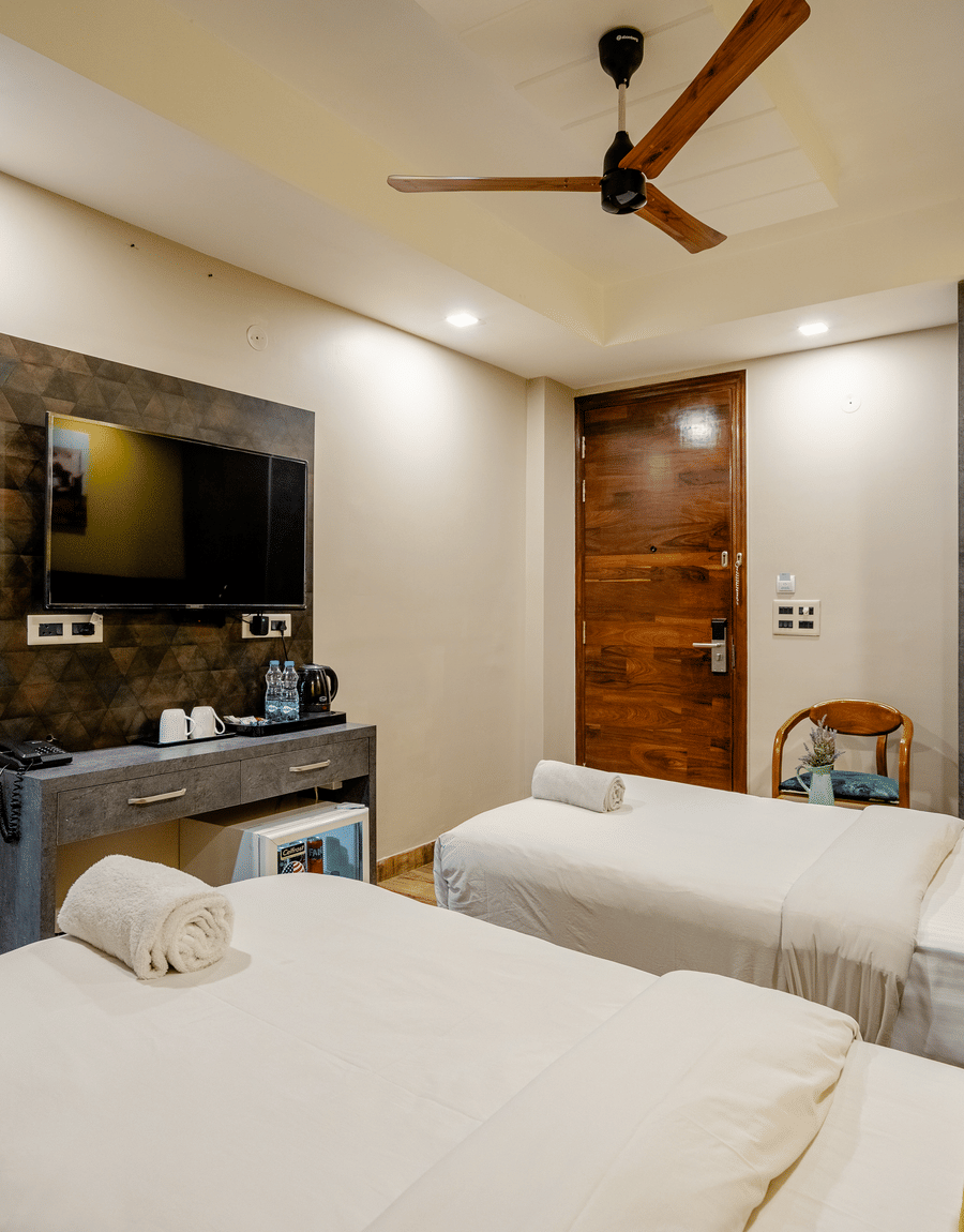 Twin beds facing a wall-mounted TV and console in the Deluxe Twin Room at Lime Tree Hotel Near Medanta, Gurgaon