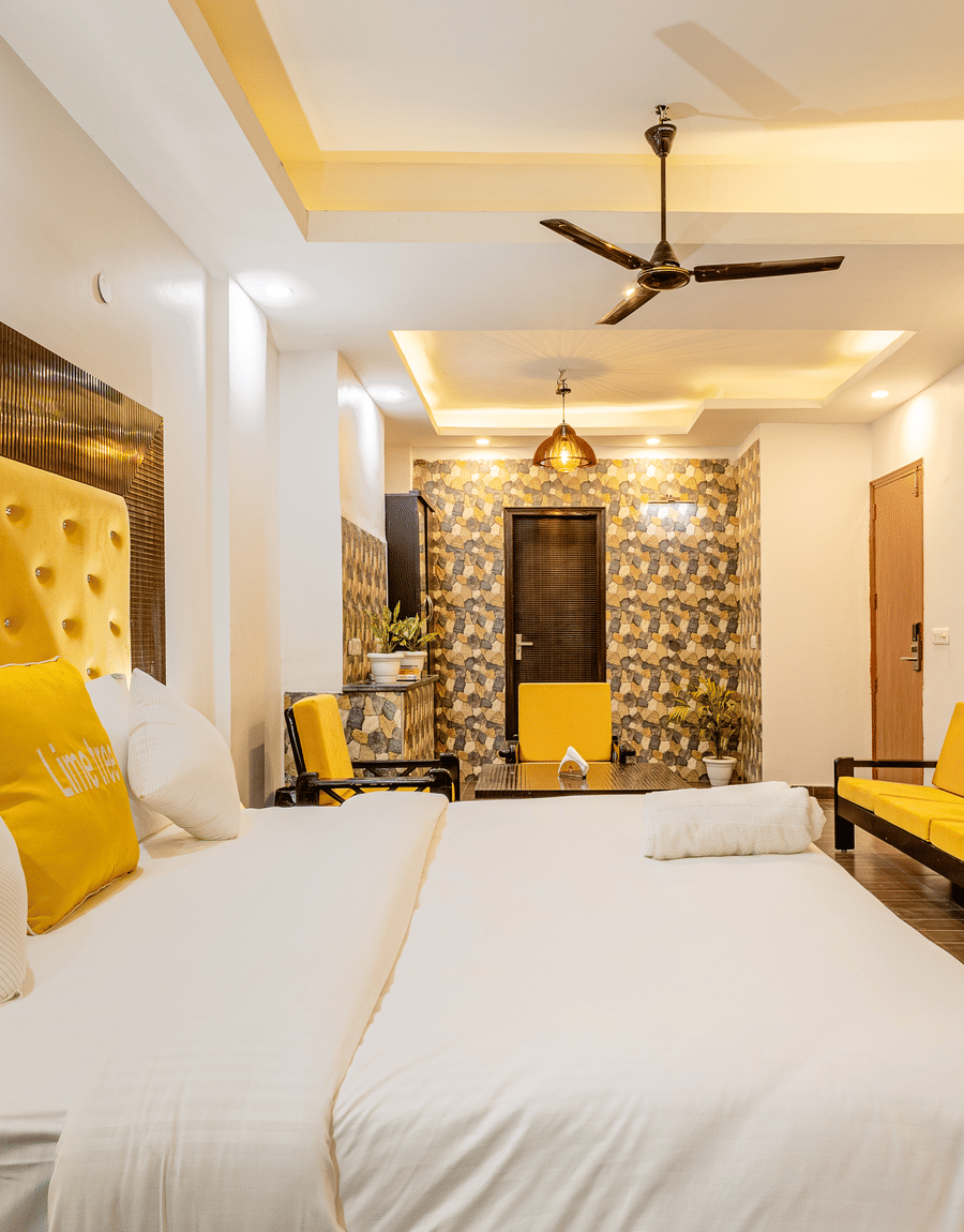 Suite with a yellow tufted king bed and yellow sofa seating at Lime Tree Hotel and Banquet, Millennium City Centre