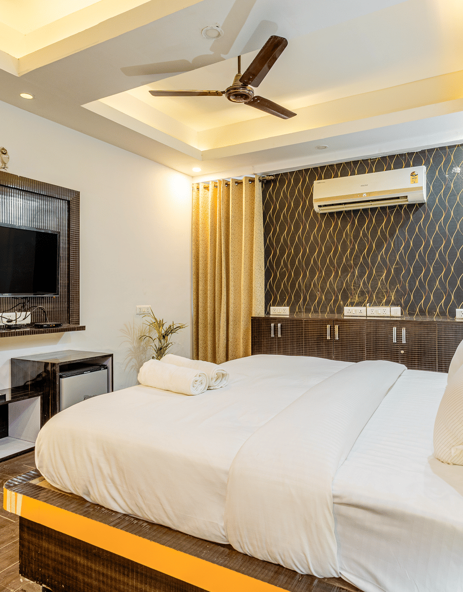 King bed facing a wall-mounted TV in the Superior King Room at Lime Tree Hotels and Banquet Hall Near Huda Metro