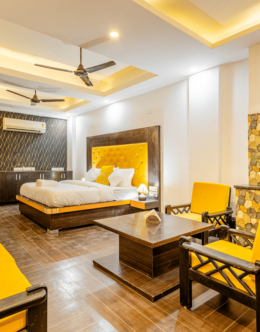 Suite with a king bed, yellow armchairs, a sofa and a coffee table at Lime Tree Hotels and Banquet Hall Near Huda Metro