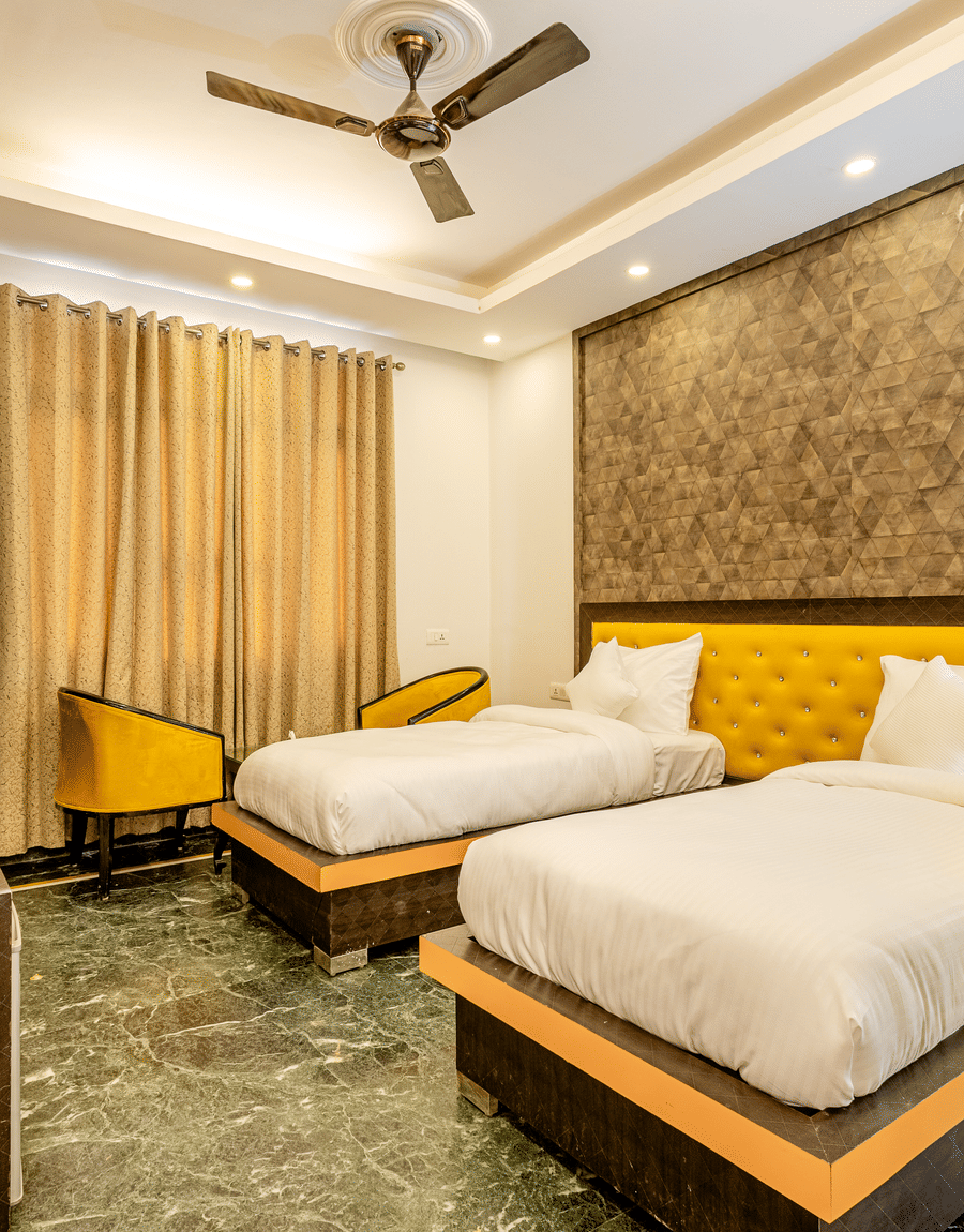 Twin beds with a yellow tufted headboard and an armchair in the Superior Double or Twin Room near Huda Metro, Gurgaon