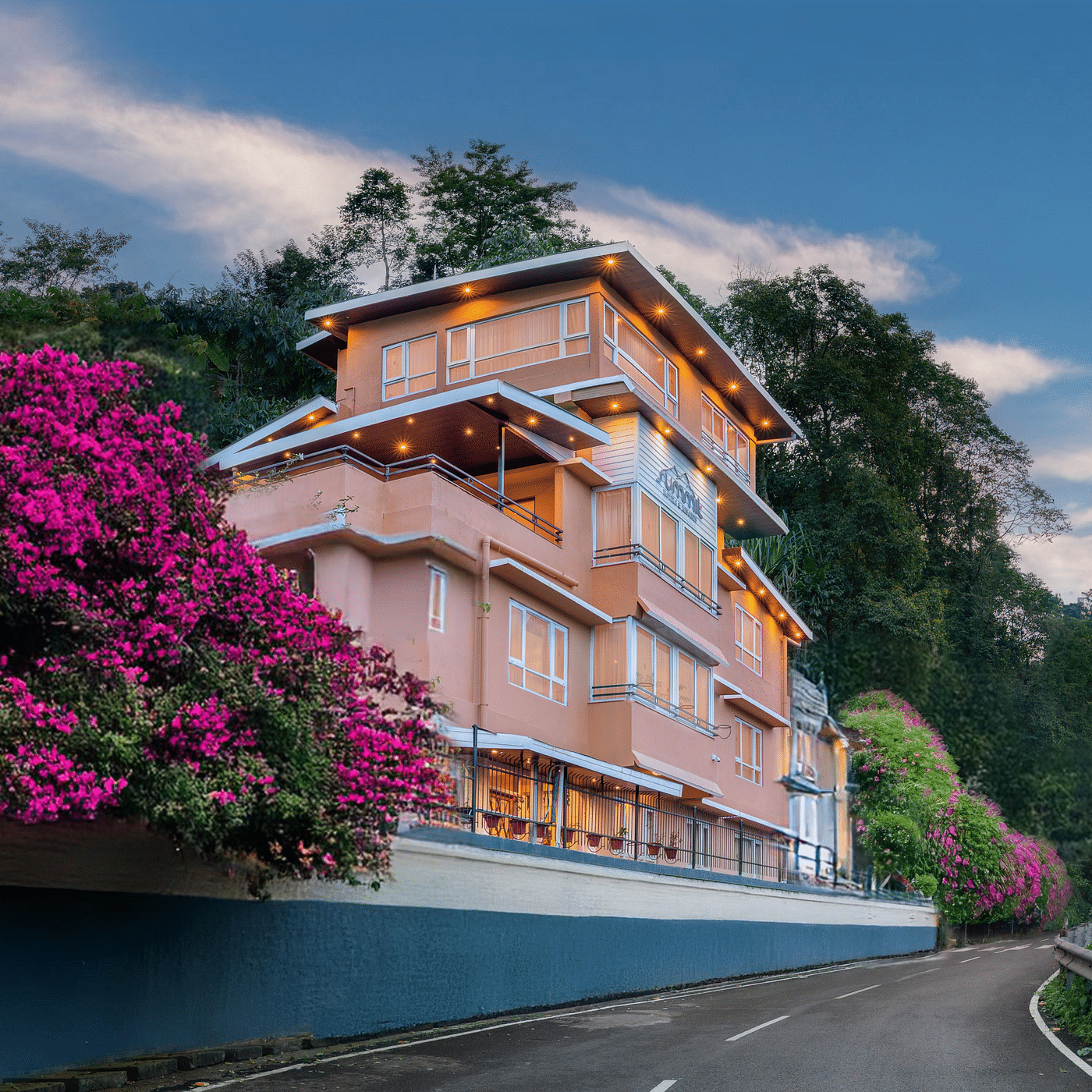 Facade of Summit Bougainvillea Tea Resort in Kurseong, framed by vibrant Bougainvillea plants, with a stunning sunset sky in the background