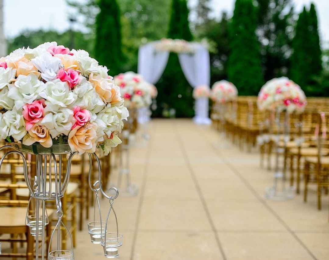 Elegant outdoor wedding ceremony setup with floral arrangements and an aisle.