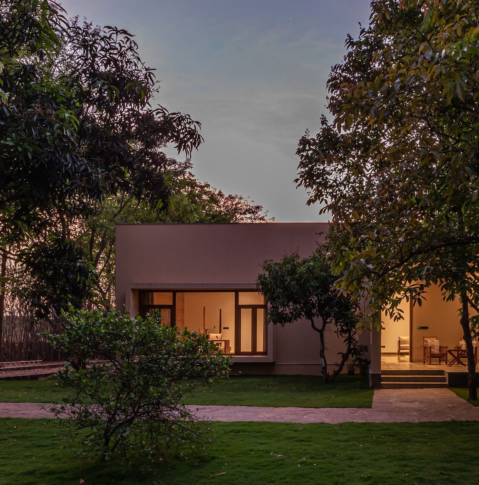 A view of the exterior of a cottage at Shreyas Retreat surrounded by trees and landscaped lawns