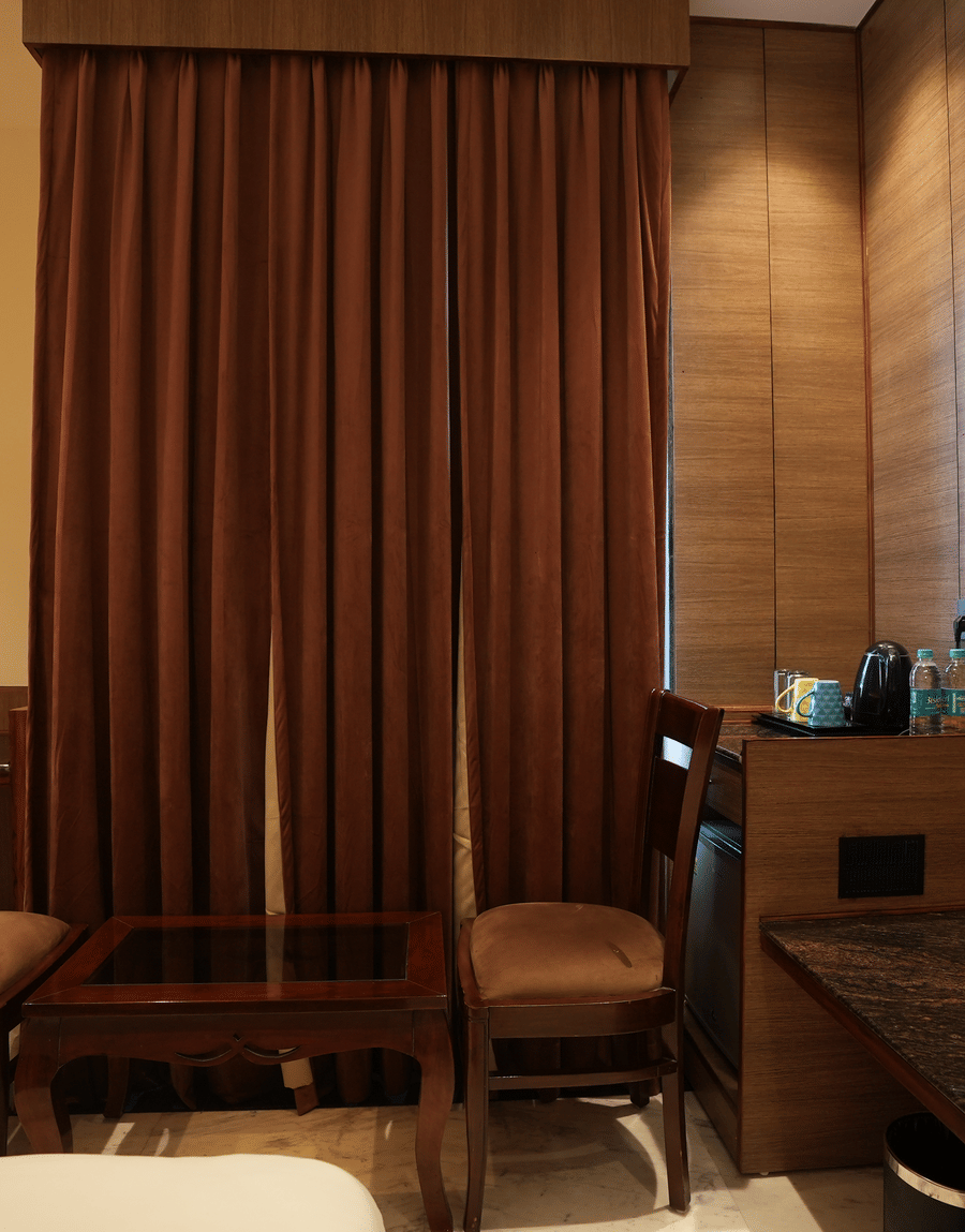Work desk and chair setup with brown curtains at Lime Tree Hotel Near India Expo Mart, Greater Noida.