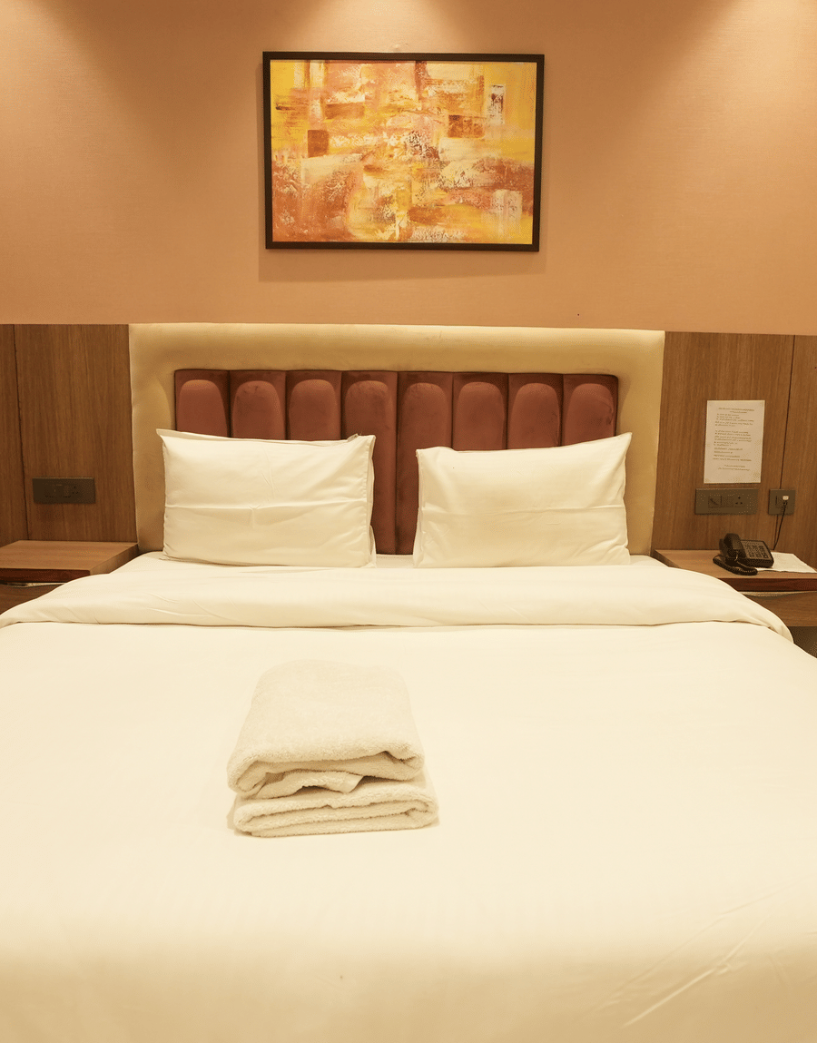 Neatly arranged king size bed with wall art at Lime Tree Hotel Near India Expo Mart, Greater Noida.