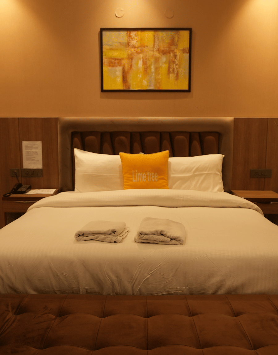 Room with king size bed, pillows, and soft lighting at Lime Tree Hotel Near India Expo Mart, Greater Noida.