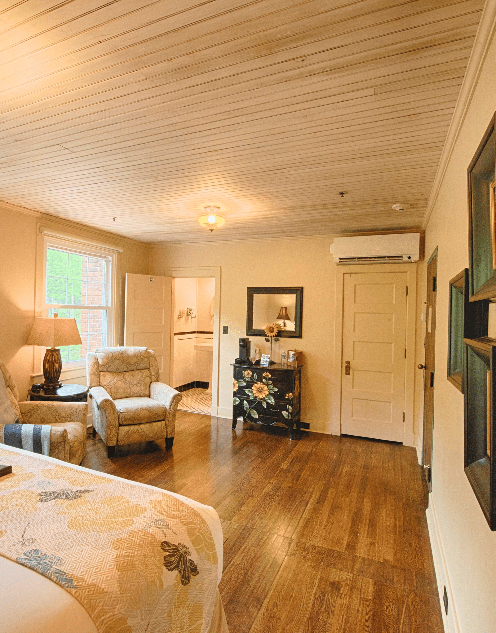 corner view image of a double bed with several frames wall mounted on the wall opposite to the windows - Historic Tapoco Lodge