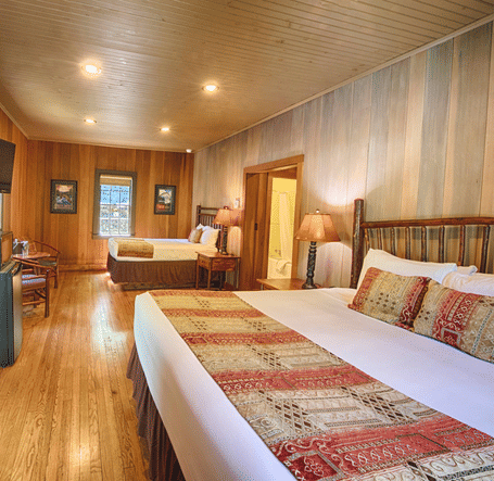 two double beds placed in a bedroom with a door in the middle of them - Historic Tapoco Lodge
