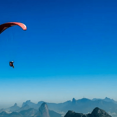 Image of a person paragliding over a mountain range