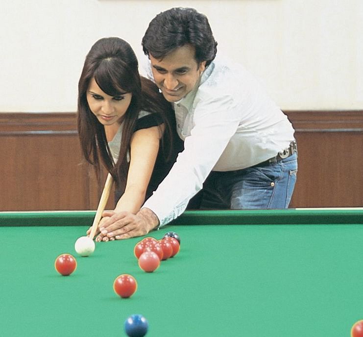 A man teaching a woman how to play pool at Nirvana Luxury Hotel, Ludhiana..