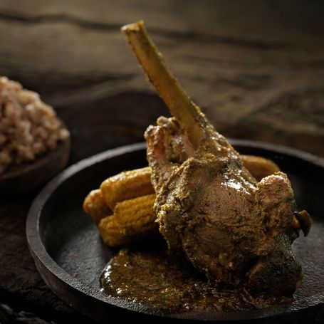 Roasted lamb shank with sauce, corn and rice.