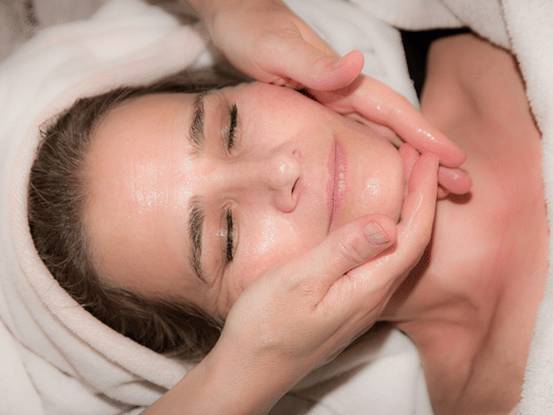 A woman receiving a facial massage at a spa.