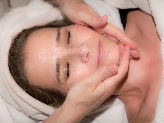A woman receiving a facial massage at a spa.