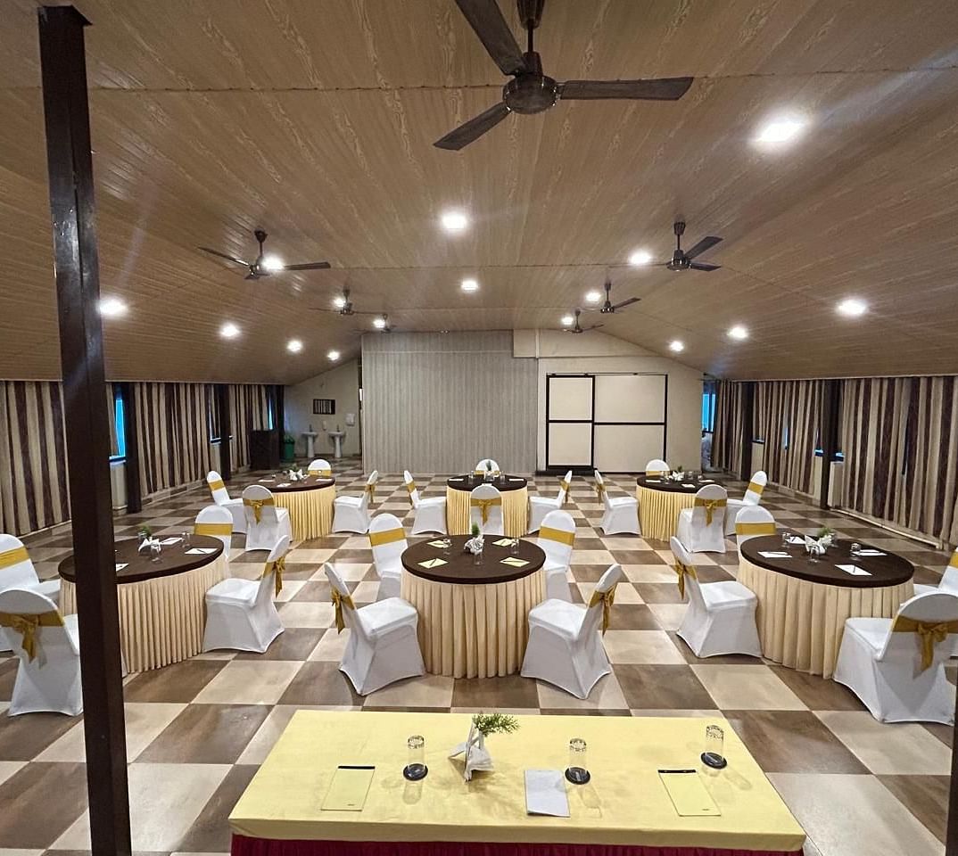 An indoor event space is shown from a different angle, highlighting the table settings | Ballroom | Woodstock Resorts, Coorg