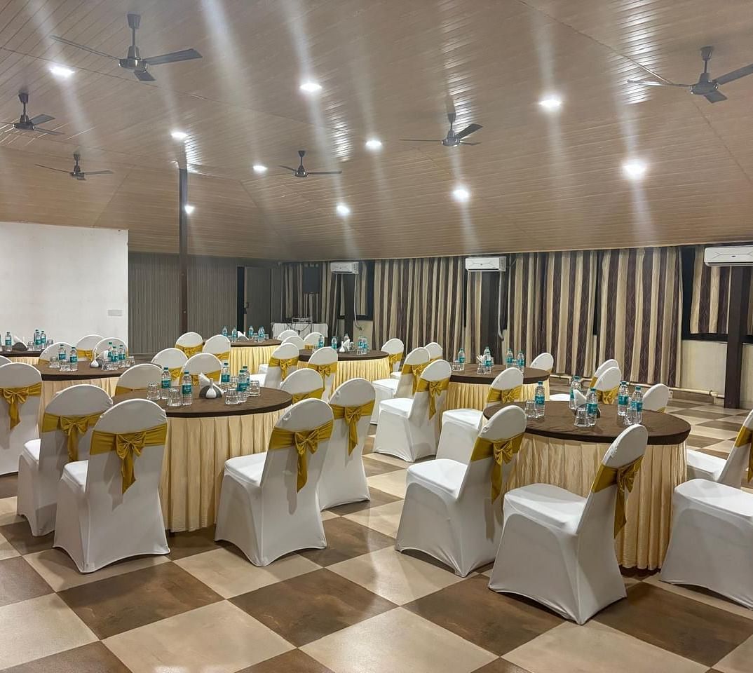 The banquet hall setup with round tables and chairs | Ballroom | Woodstock Resorts, Coorg