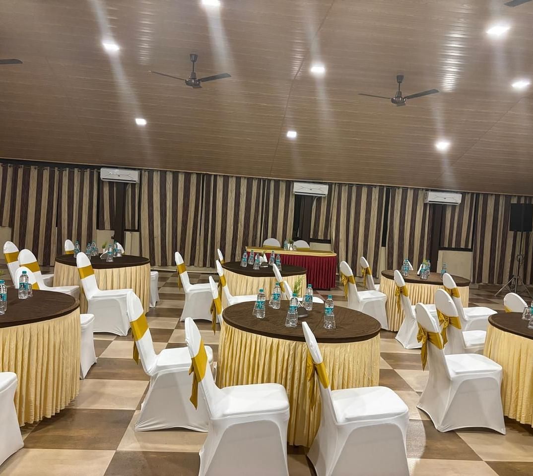 A table setting with floral centrepieces and chairs in a banquet hall | Ballroom | Woodstock Resorts, Coorg