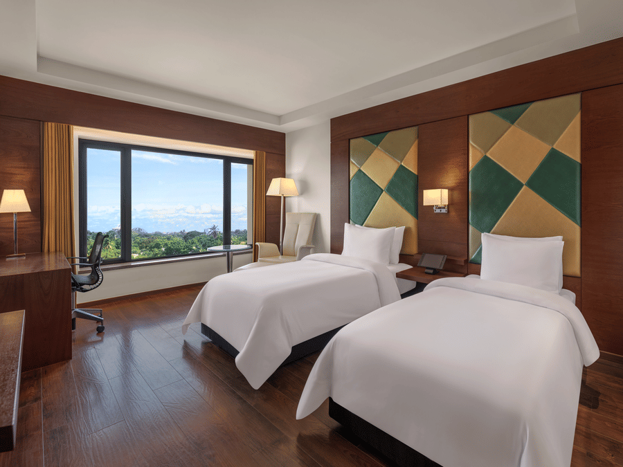 Twin bed room with decorative wall and lights mounted on them at The Residency Towers Coimbatore.