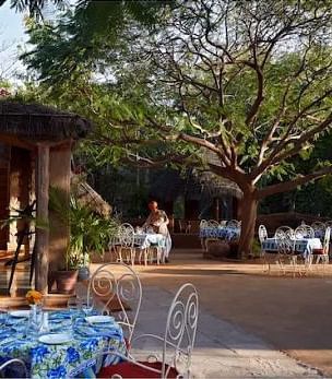 An image of the Taasli Restaurant at Manvar Shergarh with its outdoor seating arrangement with the backdrop of trees - Manvar Resort & Desert Camp