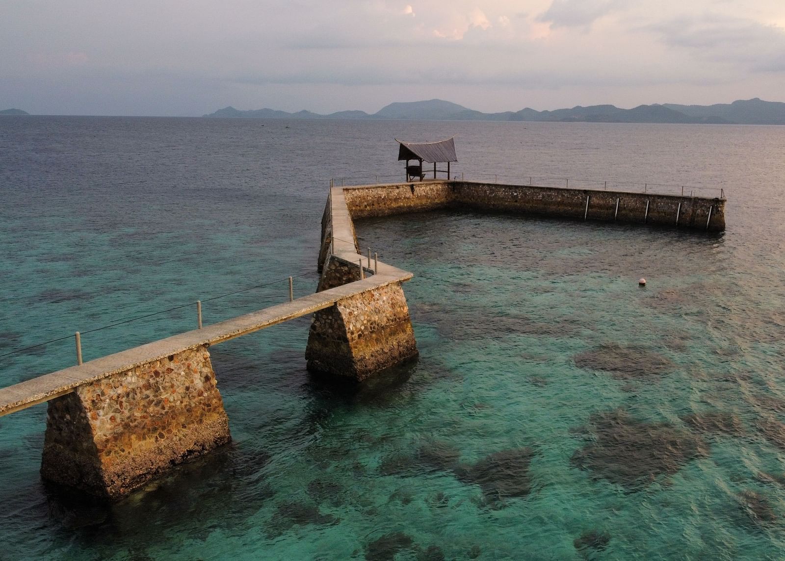 Pier extending into the ocean with Flower Island Resort buildings at the shore.