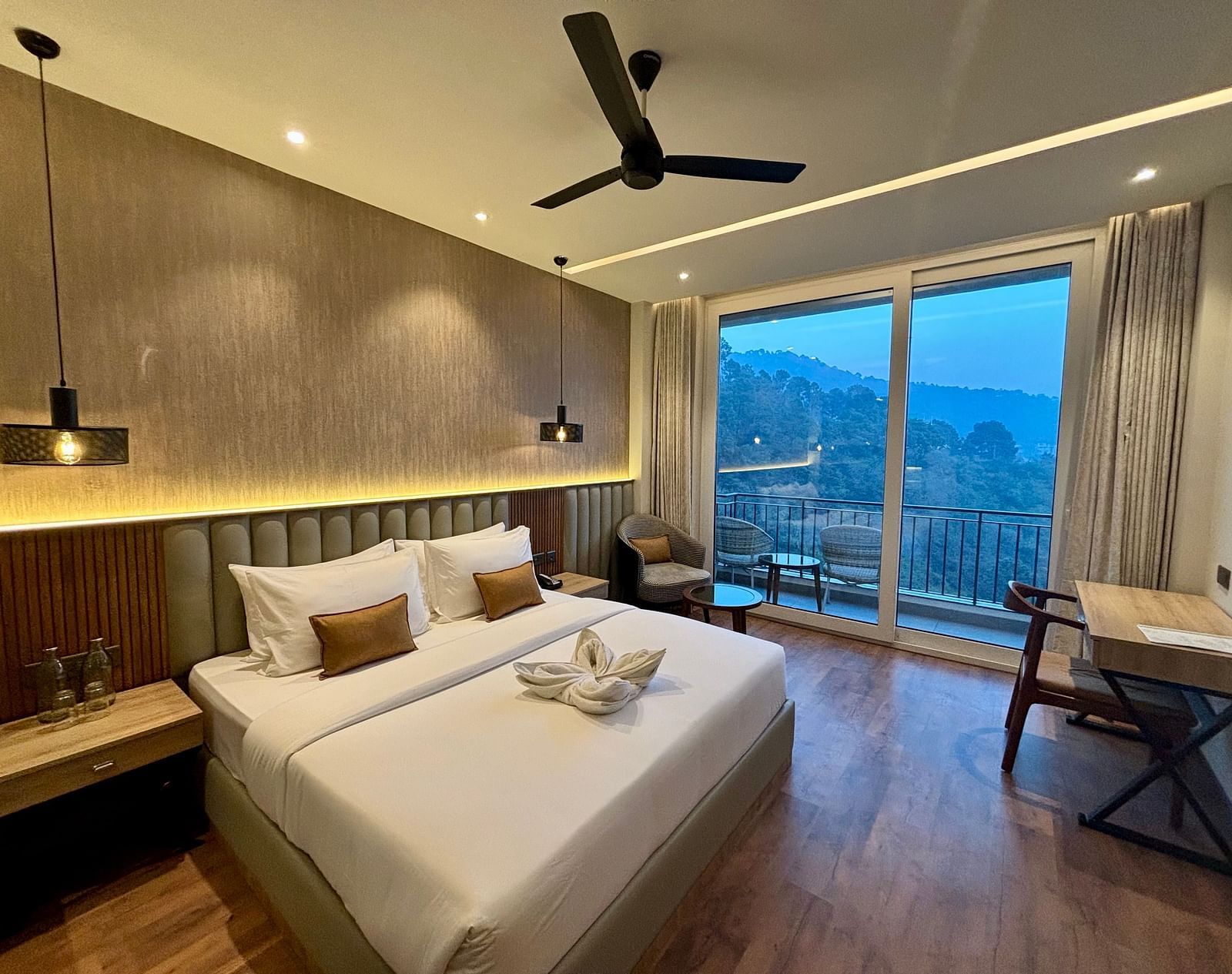Cosy double bedroom with wooden flooring, ceiling fan, and balcony offering scenic views – ARNISA Boutique Hotel