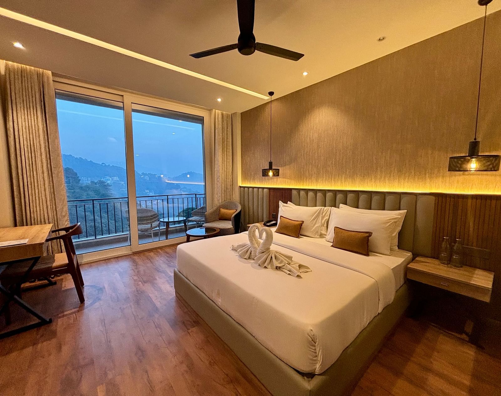 Elegant bedroom with large windows, wooden accents, and a scenic balcony view – ARNISA Boutique Hotel