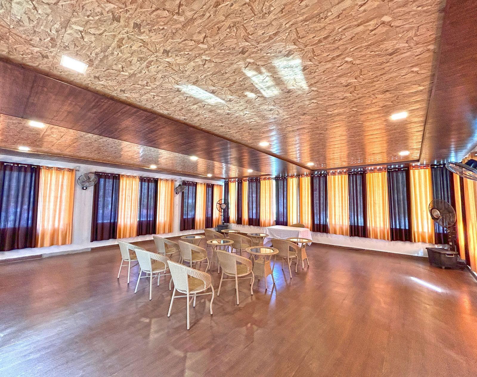 A conference hall with ambient lighting and chairs facing the stage at DLS MJ River Resort, Rishikesh.