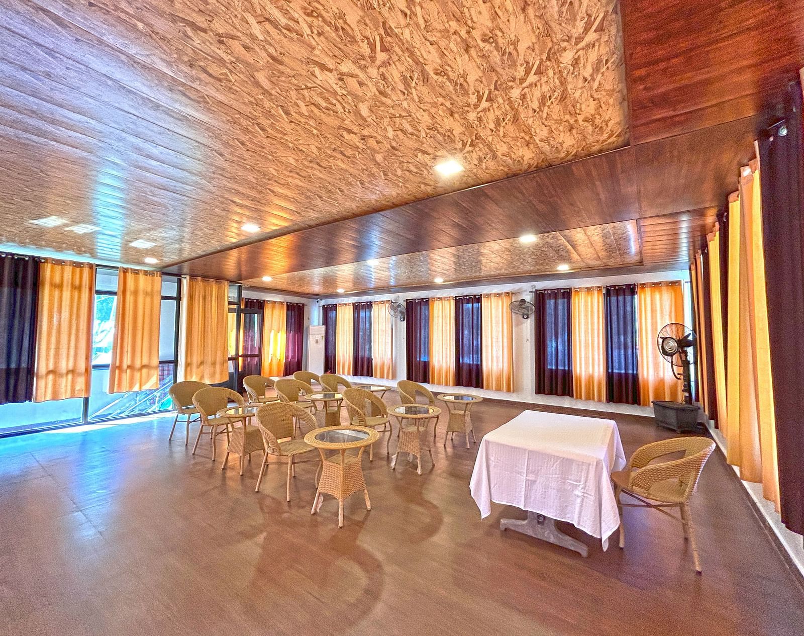A conference hall with ambient lighting and chairs facing a white table at DLS MJ River Resort, Rishikesh.