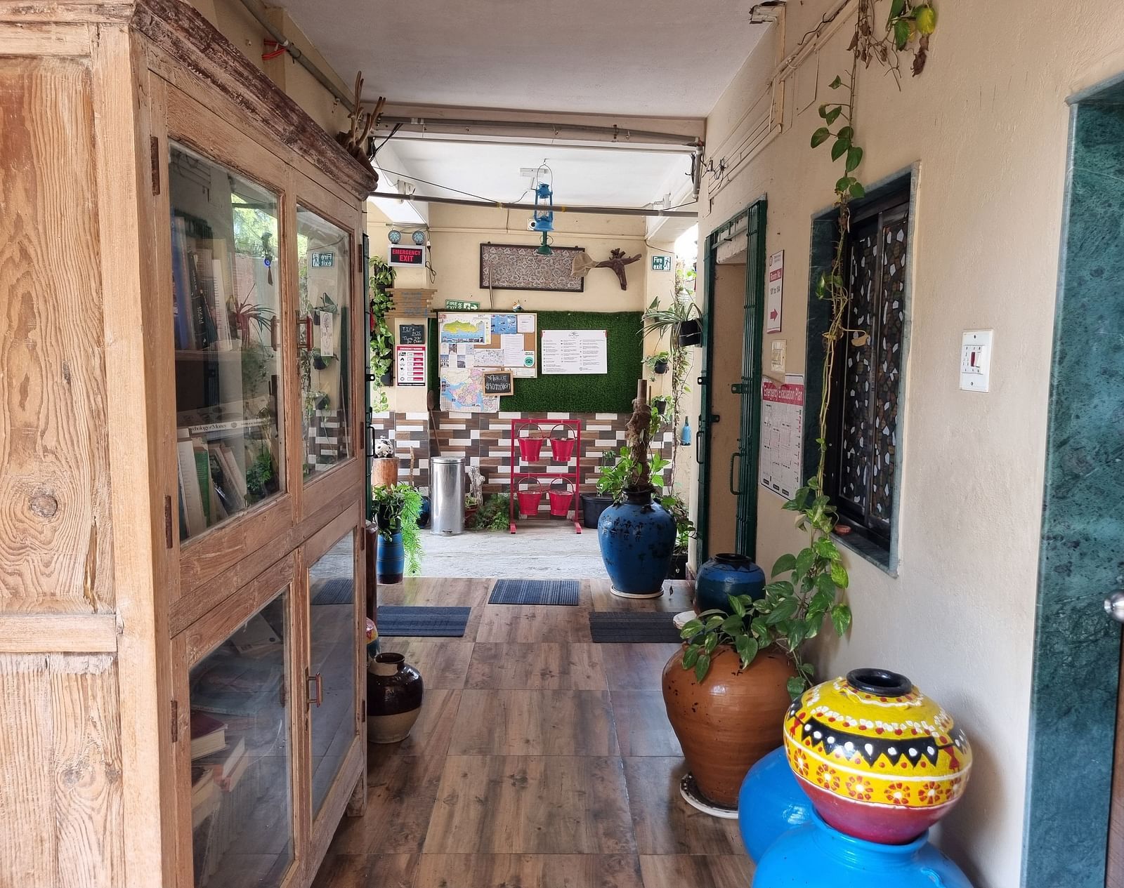 The corridor at the Dream Vision Guest House in Diu featuring a huge wooden cabinet along with several potted plants.